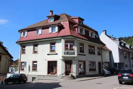 Altes Schwarzwaldhaus mit roten Dachelementen und blühenden Fensterkästen.