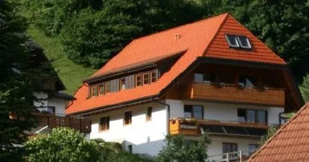 Traditionelles Schwarzwaldhaus mit rotem Ziegeldach und Balkon.