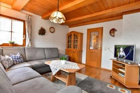 Gemütliches Wohnzimmer mit Holzdecke, Sofa, Fernseher und rustikaler Einrichtung im Schwarzwaldstil.