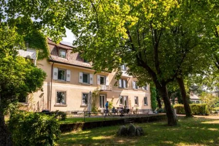Charmantes Schwarzwald-Hofgut mit Garten und Baum im Vordergrund.
